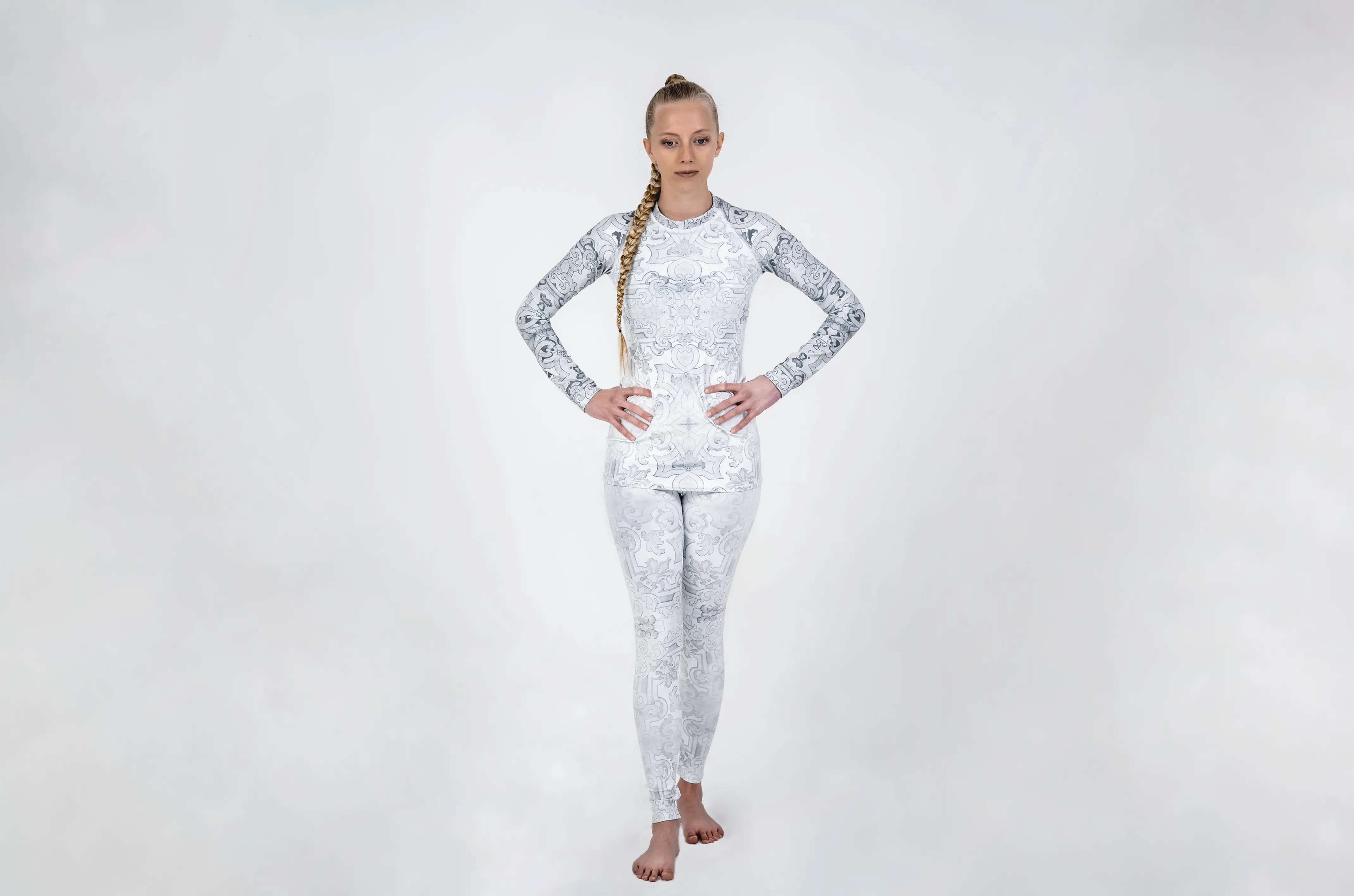 Model posing with white patterned rash guard and leggings.