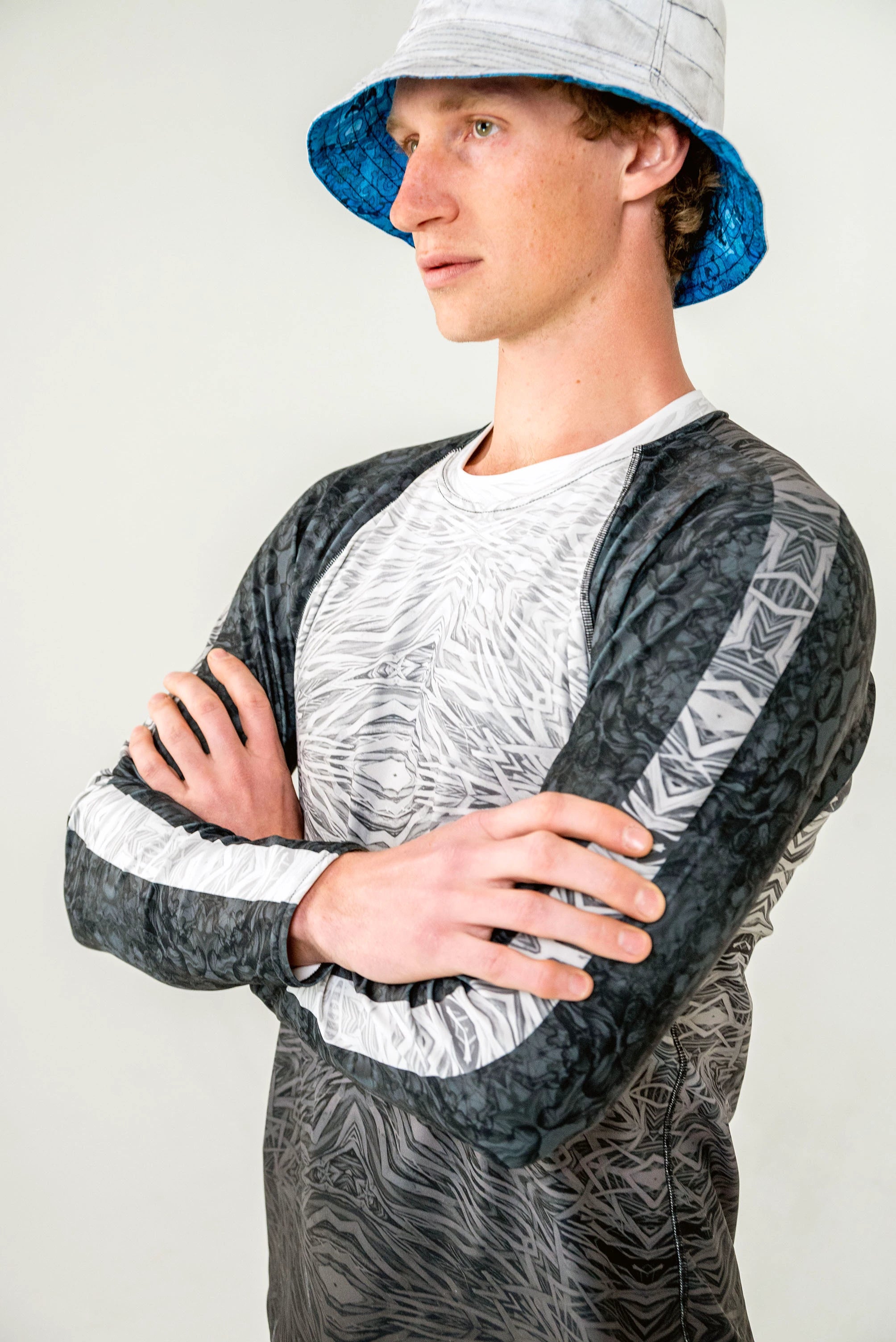 Model wearing blue and white bucket hat with a black and white rash guard.