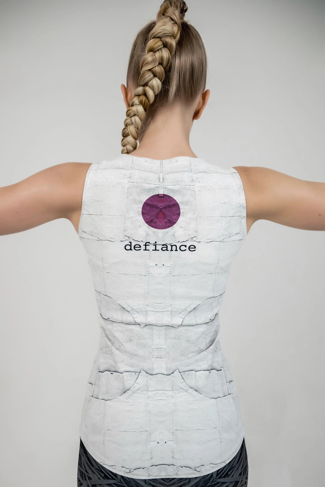 Model turned around wearing a white tank top featuring the Defiance logo.