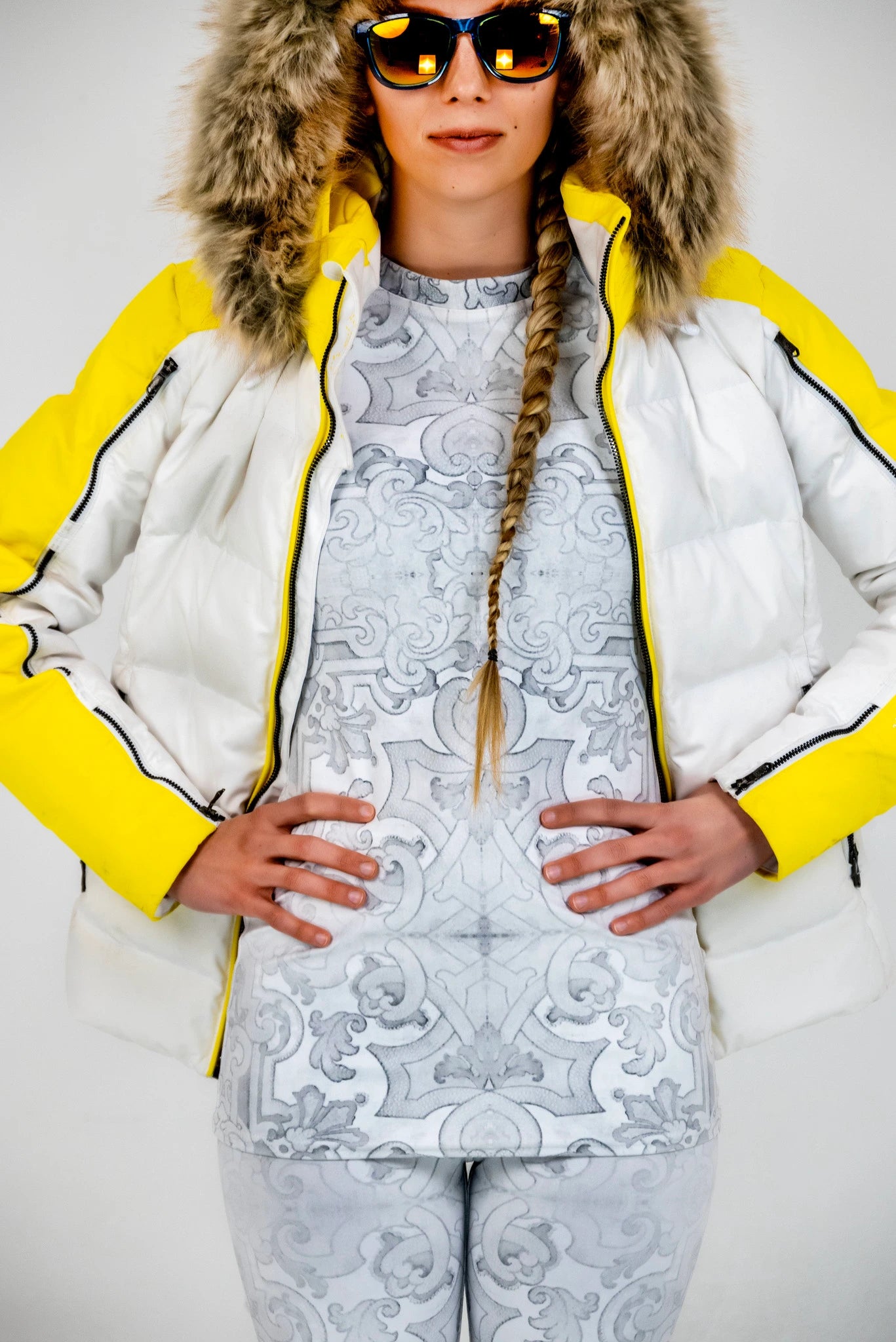Model wearing white rash guard and white leggings with a large puffer jacket.